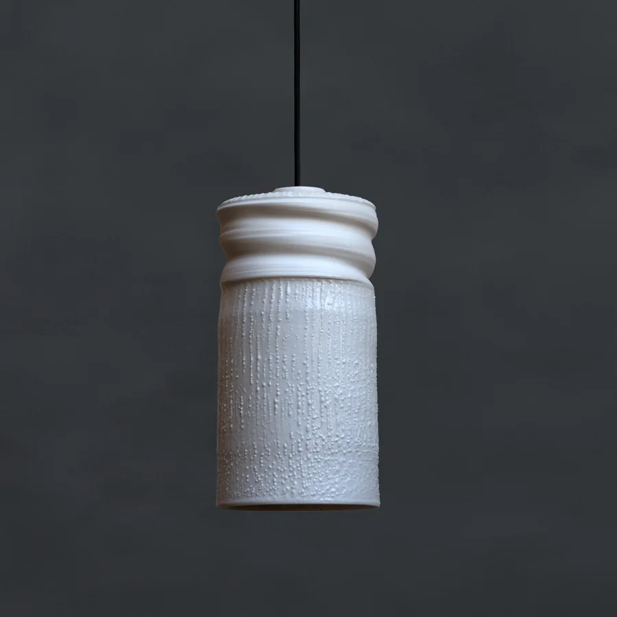 Štíhlá válcová lampa se žebrovanou horní částí na černém kabelu